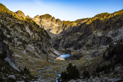 Valle montañoso con los primeros rayos de sol y un lago al fondo