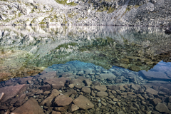 Rocas en el fondo de un lago con aguas cristalinas y reflejos